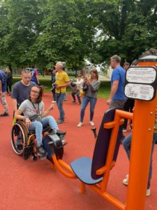 Résidents et visiteurs essayant les agrès de sport adaptés, dont un appareil accessible en fauteuil roulant