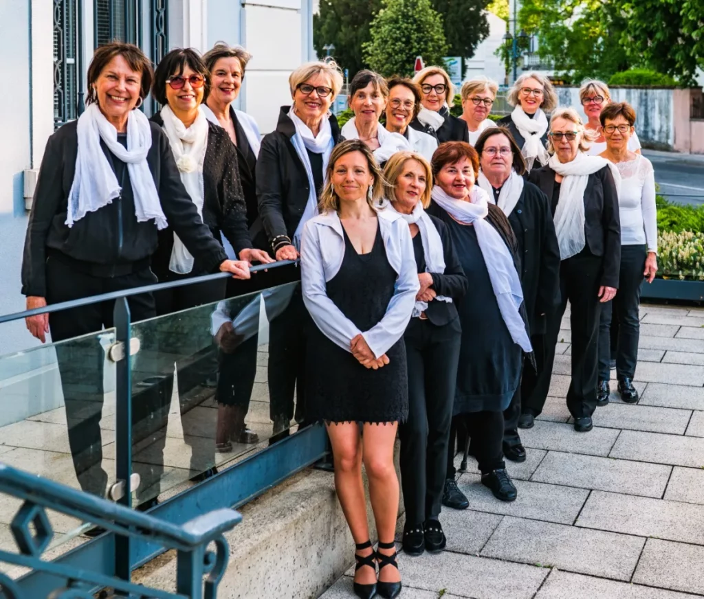 La chorale Cœur et Voix posant en extérieur, les choristes en tenue noire et écharpe blanche